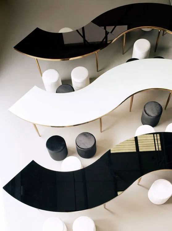 Black and white serpentine tables with velvet poufs